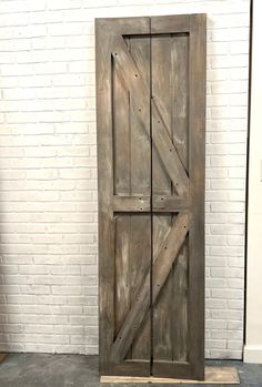 an old wooden door in front of a white brick wall