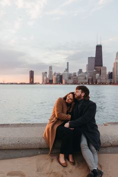 a man and woman sitting next to each other near the water