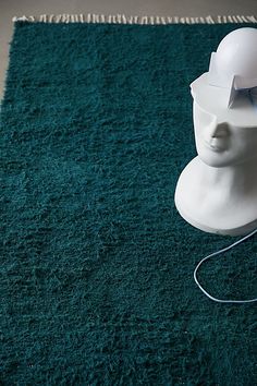 a white helmet sitting on top of a blue carpet next to a lamp and rug