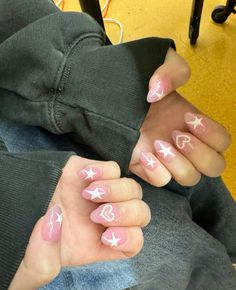 a person with pink and white nail designs on their hands, sitting in a chair