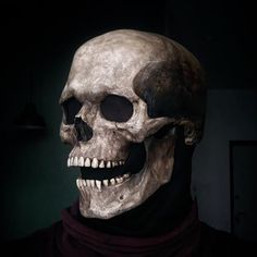 a man wearing a fake skull mask in a dark room