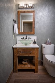 a bathroom with a toilet, sink and mirror in it's corner area next to a wooden cabinet