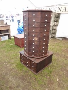 two wooden chests stacked on top of each other in front of a white tent and grass