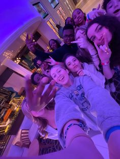 a group of people taking a selfie in the middle of a room with purple lighting