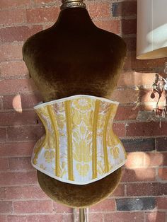 One of a kind underbust corset made in ivory and metallic gold silk brocade. The corset is made with a strength layer of Coutil and is boned with a mixture of flat and spiral steel bones, it is back lacing only.   The corset measures 29" at the waist so would probably best suit natural waists in the region of 32-35"  Fully laced the corset measures  Underbust 33"  Waist 29"  Upper hip 41"  Length at front centre 11" Elegant Gold Wedding Corset, Vintage White Underbust Corset, White Vintage Underbust Corset, Underbust Wedding Corset Belt With Boned Bodice, Underbust Corset Belt With Boned Bodice For Wedding, Cream Fitted Corset With Corset Back, White Boned Bodice Corset For Costume, White Underbust Corset For Costume, White Underbust Corset Belt With Boned Bodice