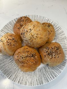 four rolls on a plate with sprinkled seeds