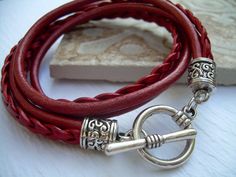 a red leather bracelet with silver clasps and a metal hook on top of it