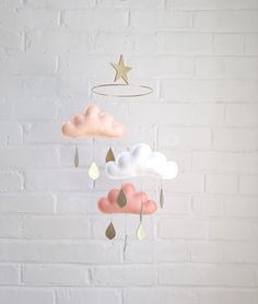 a white brick wall with a cloud mobile hanging from it's side and a gold star on top