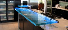 a glass counter top in a kitchen with black cabinets and stainless steel appliances on the wall