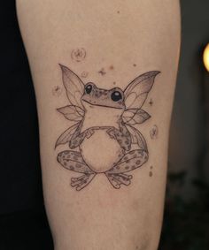 a small frog tattoo on the left thigh and right leg, with dots around it