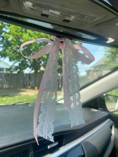 a pink ribbon tied to the back of a car's dash board with lace on it