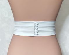 "Introducing our handmade Burgundy Bridal Belt, a stunning accessory that will add an elegant touch to your wedding dress. Made from top-quality Italian mulberry silk, this belt features a tight elastic band base for a comfortable fit. With a width ranging from 1/2\" to 3\", you can choose the perfect size to complement your gown. Fabric belts: Italy mulberry silk\\ Satin Duchess\\ Matte satin\\ Satin crepe + tight elastic band base. Length: As requested Clasp design: - minimalism. Clean smooth edge without decorative elements; - bow. Delicate silk bow; - buttons (pearl buttons, silk-covered buttons). Shine level: Matte satin - 1 points Satin Duchess - 2 points Mulberry silk - 3 points Satin crepe - 5 points The clasp design options include a minimalistic style with a clean, smooth edge, a Elegant Fitted Corset Belt With Belt Loops, Elegant Corset Belt With Belt Loops, White Bridal Belt For Bride, Elegant Fitted Fabric Belt, Elegant Fitted Corset Belt With Sashes, White Fitted Bridal Belt For Ceremony, Fitted Satin Bridal Belt For Bridesmaid, White Satin Bridal Belt With Sashes, White Embroidered Bridal Belt For Formal Occasion