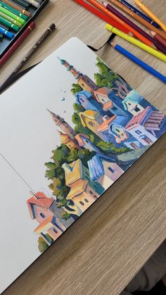 a drawing with colored pencils and markers on the table next to it is an image of a city