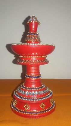 a red vase sitting on top of a wooden table