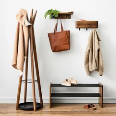 a coat rack, shoes and bag are hanging on the wall next to a bench