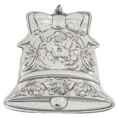 a metal bell with flowers and bows on the front, is shown in silver color