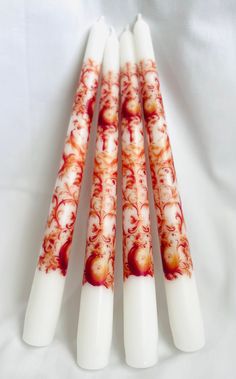 four white candles with red designs on them