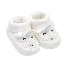 a pair of white crocheted baby shoes with a bear face