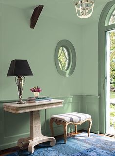 a room with green walls and blue rugs on the floor next to a table