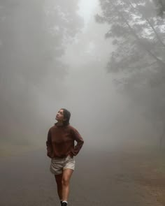 a man is running in the foggy road with his head turned to the side