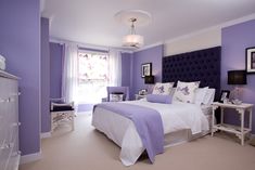 a bedroom with purple walls and white furniture