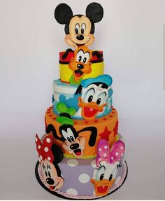 a multi layer cake with mickey mouse and friends on it's top tiers