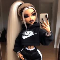 a doll with long blonde hair holding a cell phone and wearing a black nike hoodie