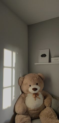 a brown teddy bear sitting on top of a chair in a room with light coming through the window