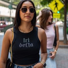 This trendy & unique Rhinestone Old English Sorority Bella Canvas Cropped Tank Top is sure to stand out on any campus! These tanks are perfect for big/little reveal, work-week fits, or bid day celebrations Picture Details ⭑ #1-4: Black tank (Tri Delta - Delta Delta Delta) ⭑ #5-8: Pink tank (Zeta - Zeta Tau Alpha) Care Instructions ⭑ Wash inside out on cold & air dry for best results ⭑ Do not dry clean ⭑ Light iron if necessary ⭑ Care instructions are included with every order. We are not respons Sorority Tank Tops, Bid Day Shirts, Tri Delta, Merch Ideas, Big Little Reveal, Bid Day, Work Week, Neck Hoodie, Pink Tank