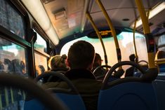 two people sitting on a bus with their backs to the camera as they look out the window