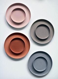 four different colored plates sitting on top of a white countertop next to each other