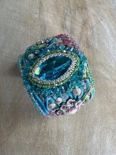 a blue jeweled box sitting on top of a wooden table