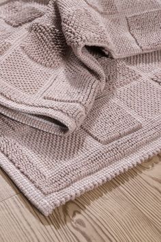 a knitted blanket laying on top of a wooden floor