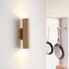 a wall mounted light on the side of a white wall next to pots and pans