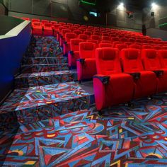 rows of red chairs in an auditorium with colorful carpeted flooring and blue walls