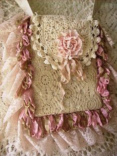 an old purse with pink flowers and lace on the bottom is sitting on a table