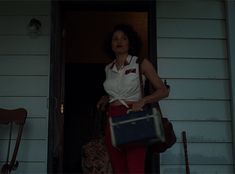 a woman holding a suitcase standing in front of a door