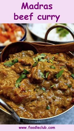 a metal pan filled with meat curry and garnished with cilantro leaves