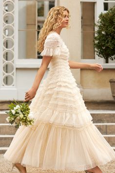 a woman in a white dress is walking down the street with her hand on her hip