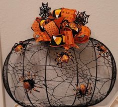 a spider web decoration with orange and black decorations on it's head, hanging from the wall