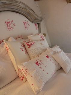 a bed with white and red pillows on top of it's headboard in a bedroom