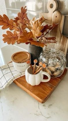 a wooden tray topped with coffee cups and autumn leaves