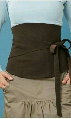 a woman wearing a brown belt with her hands on her hips and the bottom half of her waist