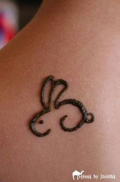 a rabbit tattoo on the back of a woman's shoulder