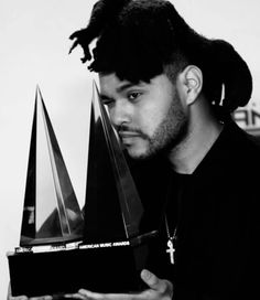 a man with dreadlocks holding an award in front of his face and looking at the camera