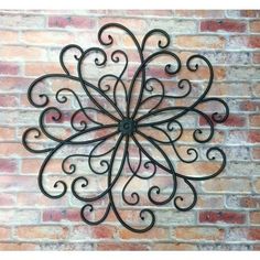 a metal wall hanging on the side of a brick building with an intricate design in the center