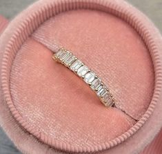 a diamond ring sits in a pink velvet box