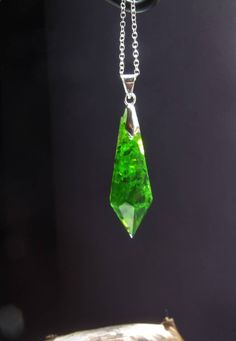 "Unique necklace in pendulum/crystal form. The pendant is filled with little glass pieces in a deep, glowing green. The pendant is 4cm tall and can be ordered with a black ribbon or silver necklace. The color of the little hanger can be chosen. This piece was handcrafted and is therefore unique.  Please note: Due to the crafting process the pieces in this form have a \"backside\". This means one of the facets can be mat, have a little edge or small bubbles. But of course all of my pieces are cra Green Resin Pendant Necklace, Green Gemstone Crystal Necklace With Round Pendant, Green Crystal Pendant Jewelry, Green Gemstone Pendant Crystal Necklace, Green Spiritual Jewelry For Party, Green Spiritual Jewelry For Parties, Faceted Green Crystal Necklace For Gift, Green Resin Round Pendant Necklace, Green Glass Pendant Jewelry