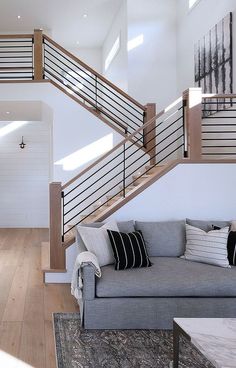 a living room with a gray couch and wooden stairs