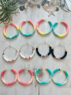 six pairs of hoop earrings with different colors and designs hanging from hooks on a wall